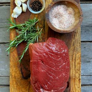 Raw Beef Top Round on a cutting board that is attractively arranged